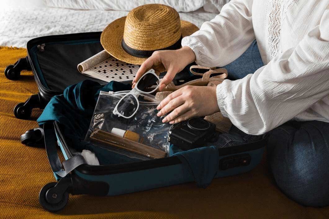 a woman is sitting on the floor packing a suitcase for a trip .