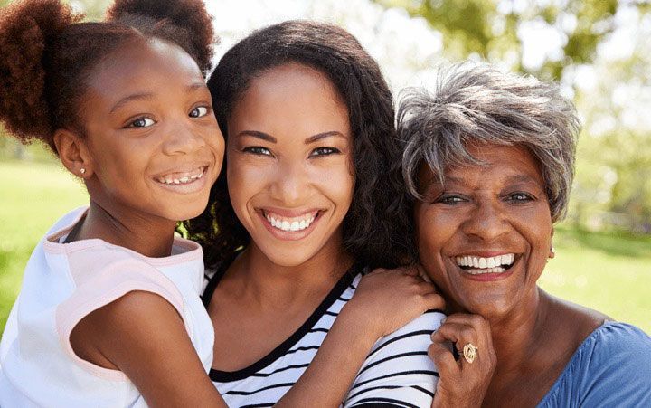a woman , a little girl , and an older woman are posing for a picture .