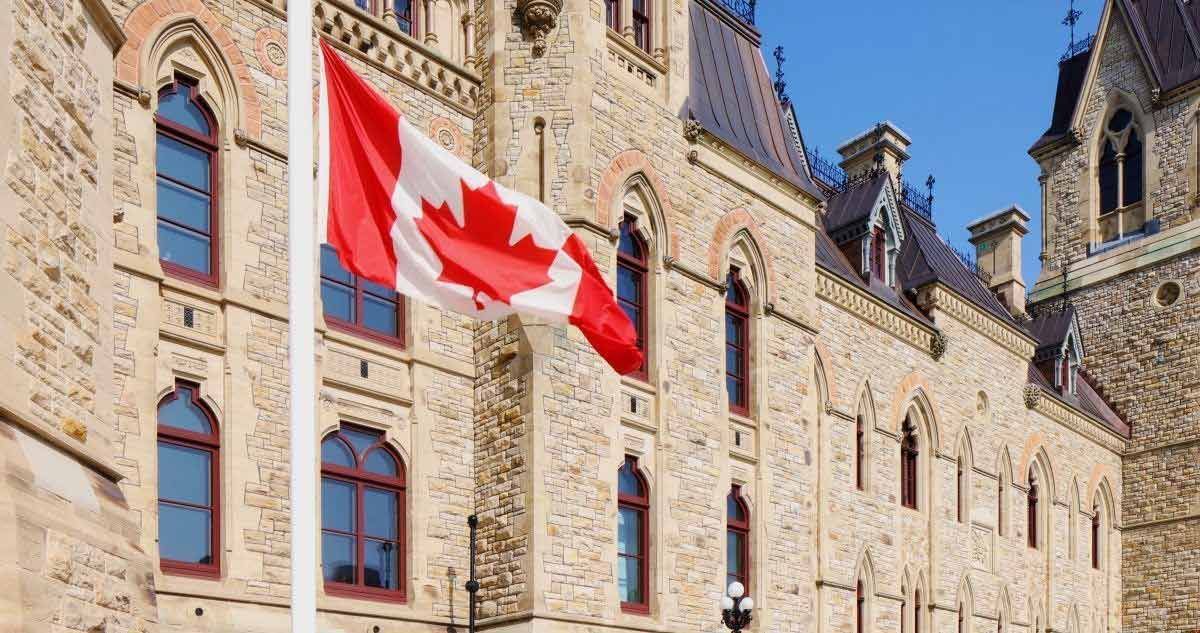 a canadian flag is flying in front of a stone building .