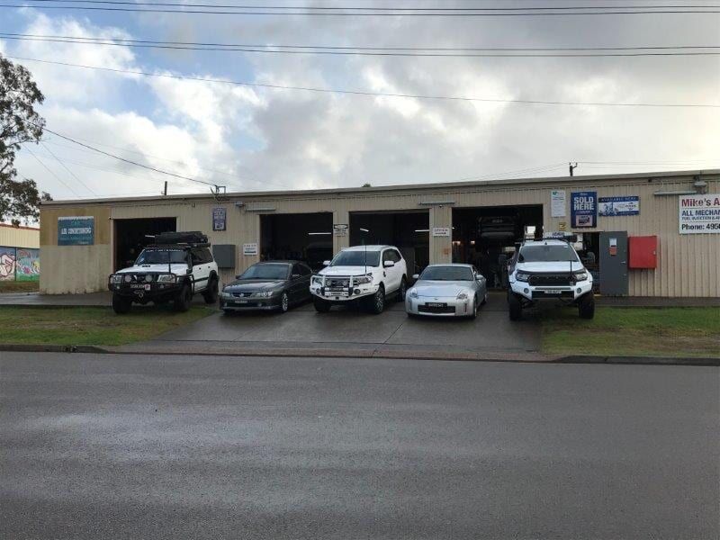 Cars Parked in Front of a Mechanic Shop With Open Garage Bays on a Cloudy Day — Mike's Automotive in Edgeworth, NSW
