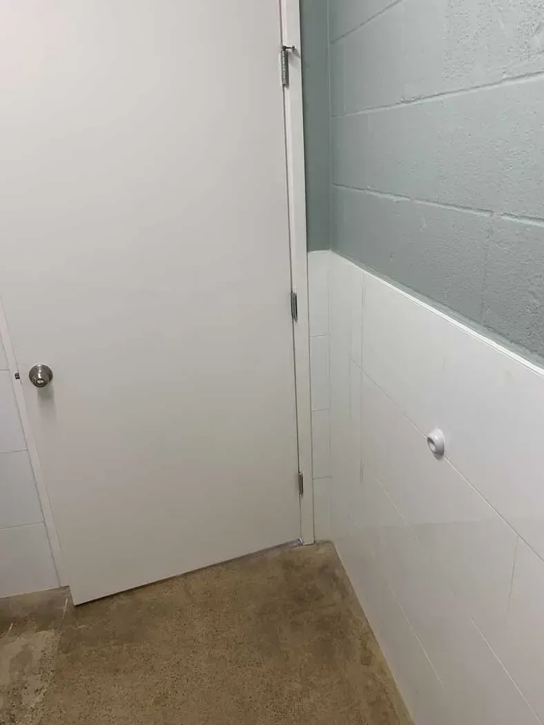 White door in a corner with painted walls: white wainscoting and light blue upper wall. Gray concrete floor.