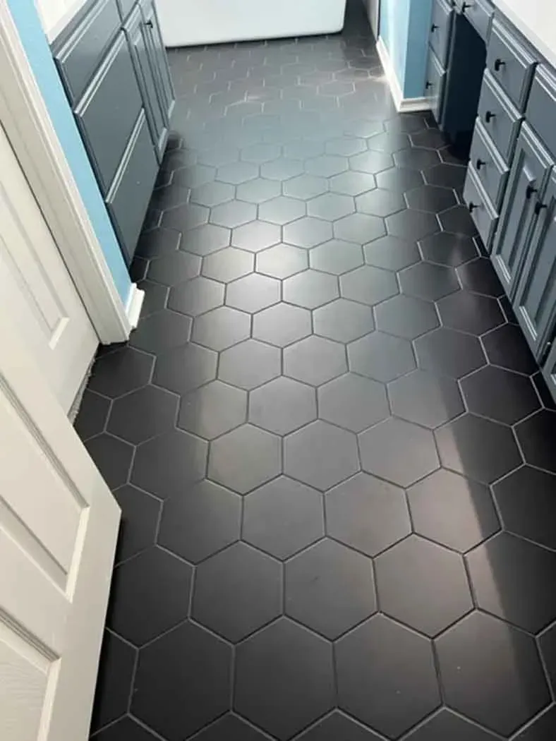 Dark gray hexagonal tile floor in a room with cabinets and a doorway.