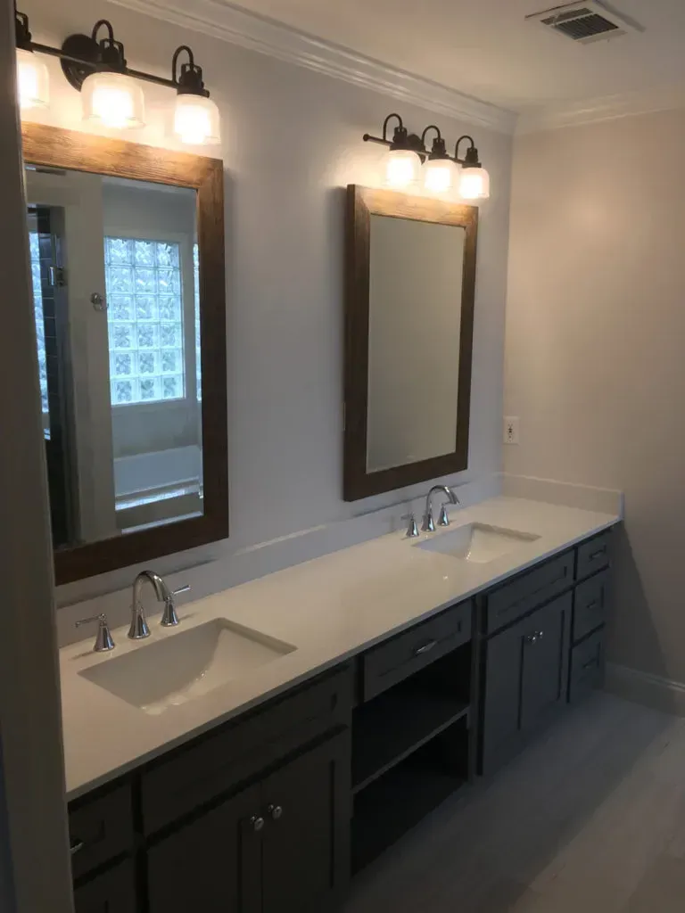 Double bathroom vanity with gray cabinets, white countertop, mirrors, and light fixtures.