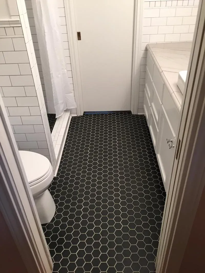 Bathroom with black honeycomb tile floor, white subway tile walls, and white vanity.
