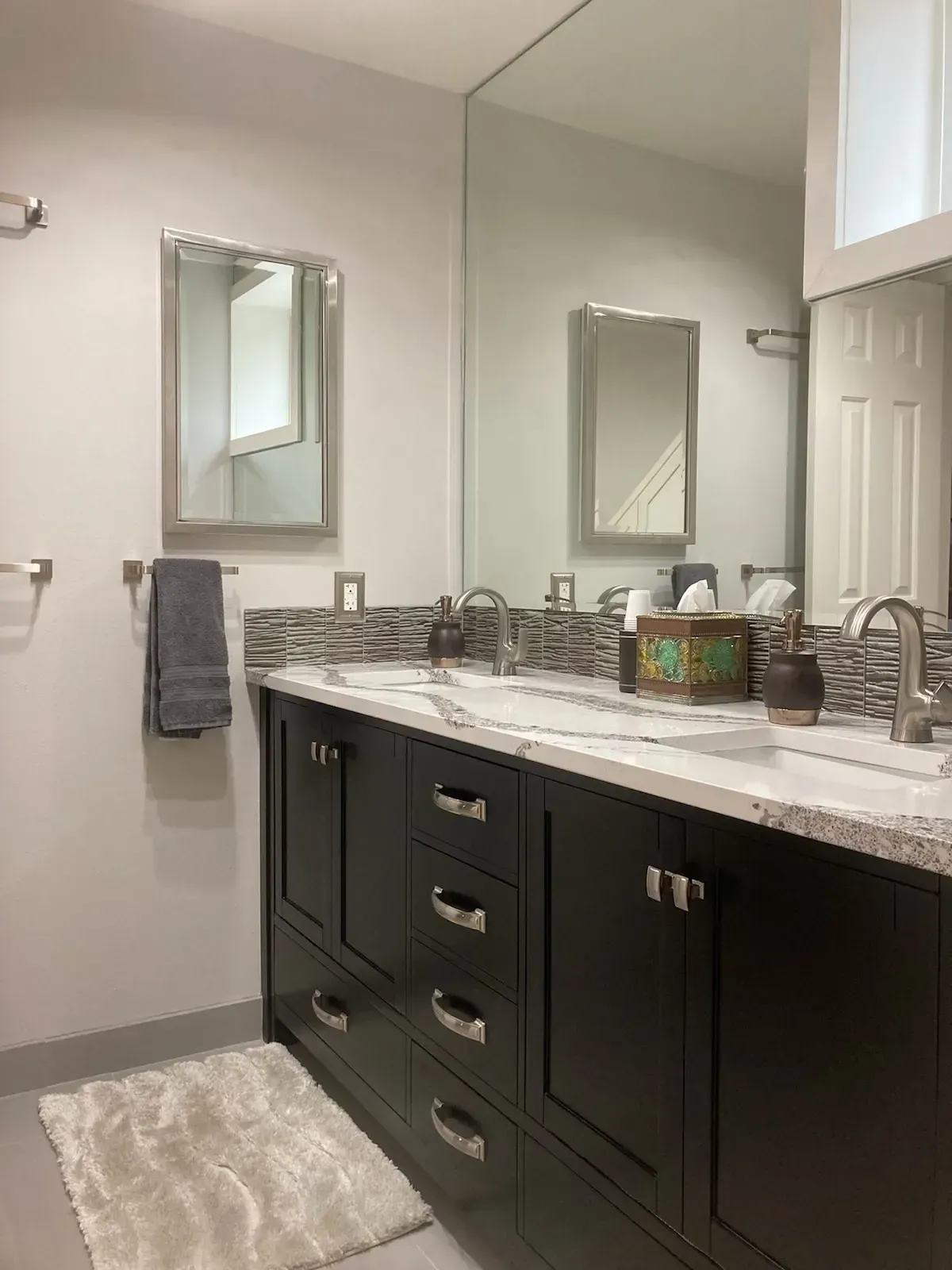 Bathroom with dark cabinets, a marble countertop, and a large mirror.
