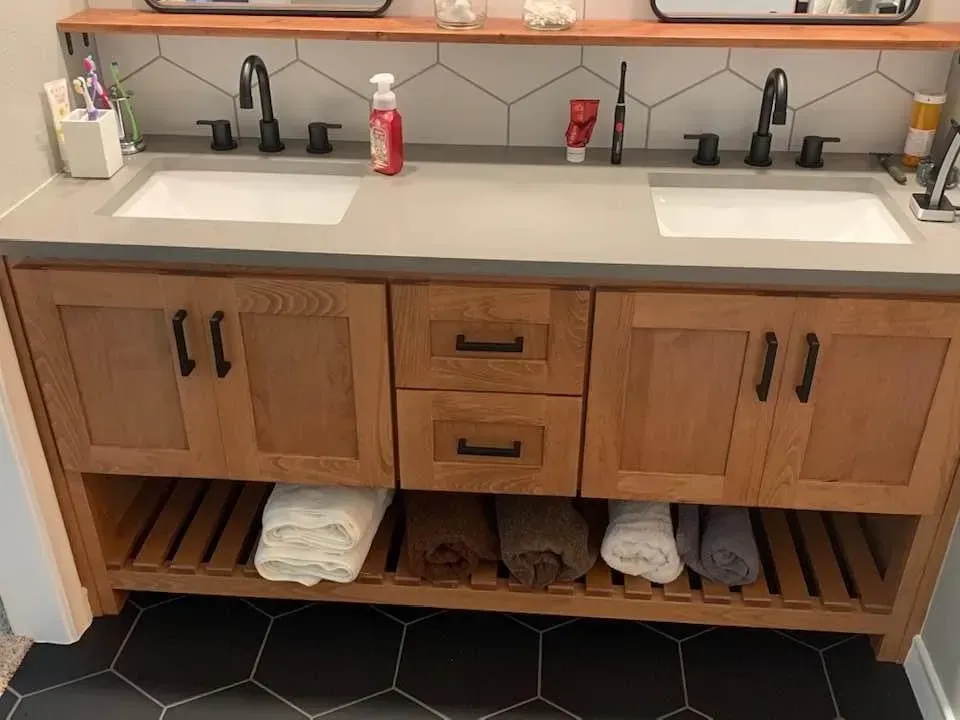 Bathroom vanity with dual sinks, wooden cabinets, black fixtures, and black and white tile.