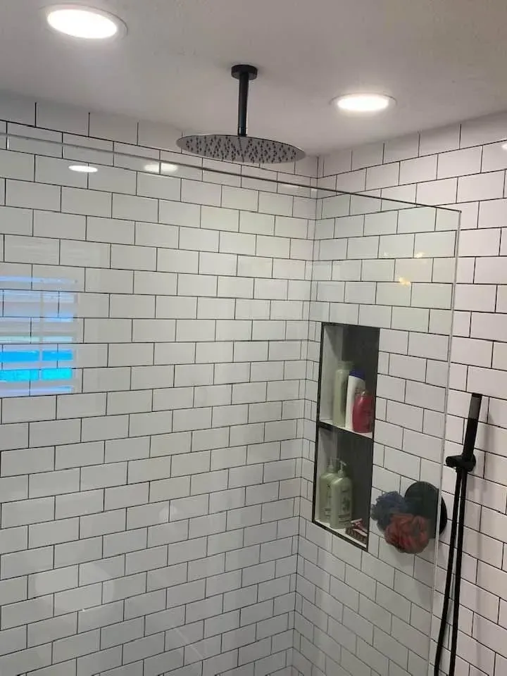 Modern shower with white subway tile, a rain shower head, and a built-in shelf.