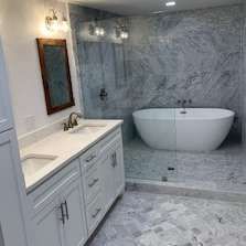 Modern bathroom with white vanity, marble-patterned walls and floor, and a freestanding tub.