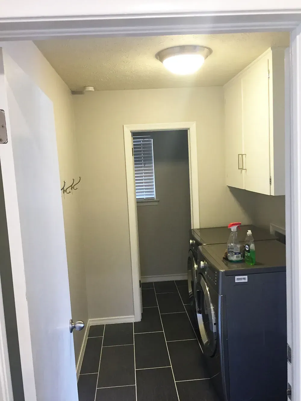 Laundry room with washer, dryer, cabinets, and a doorway to another room.