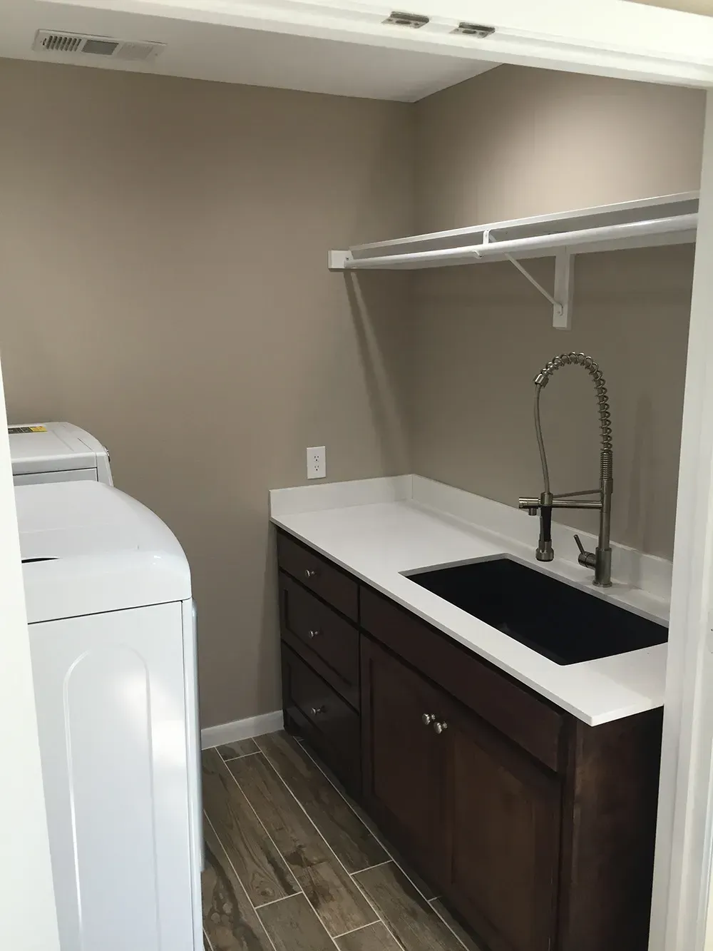 Laundry room with washer, sink, cabinets, and shelf.