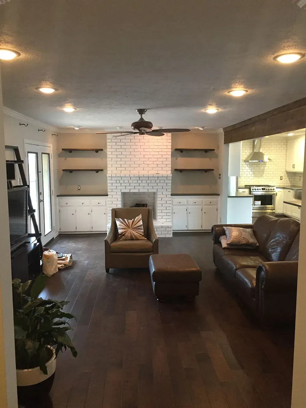 Living room with fireplace, built-ins, and dark wood floors. Brown leather sofa and chair.