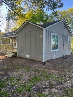 Small, gray house with white trim, porch, and windows, set in a yard.