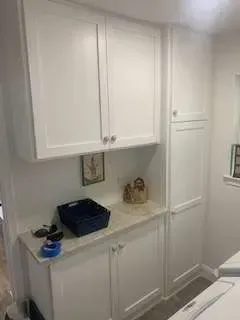White cabinets in a laundry area, with countertops and storage.