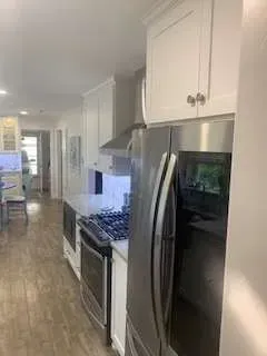 Kitchen with white cabinets, stainless steel appliances, and wood flooring.