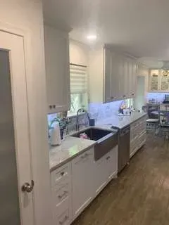 White kitchen with cabinets, stainless steel sink, and wood floors.