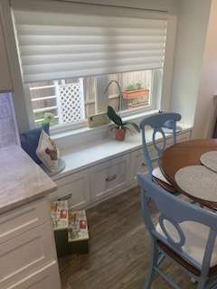 Window seat with drawers, white blinds, and light blue chairs in a kitchen.