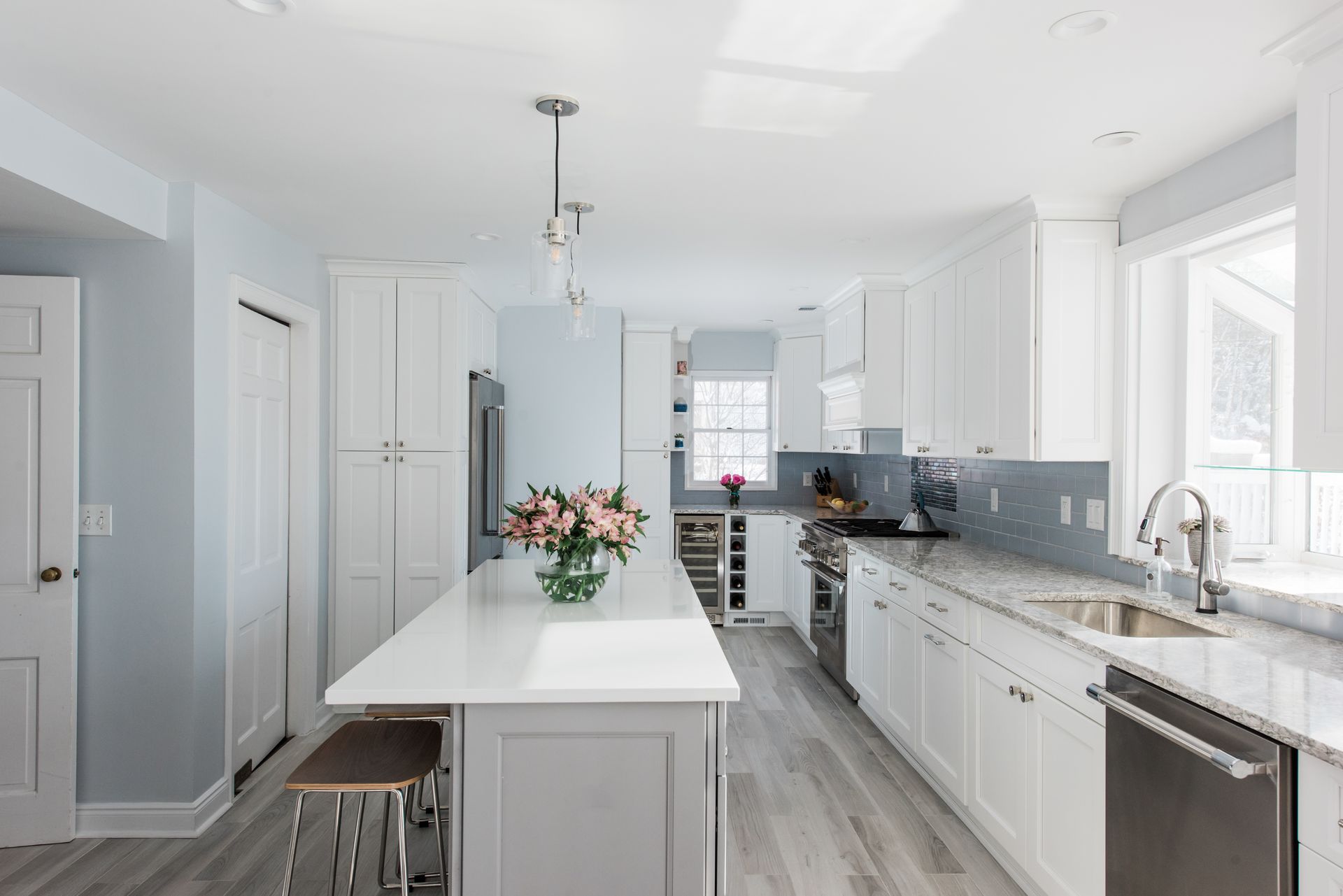 Bright, modern kitchen with white cabinets, gray island, and pale blue walls.