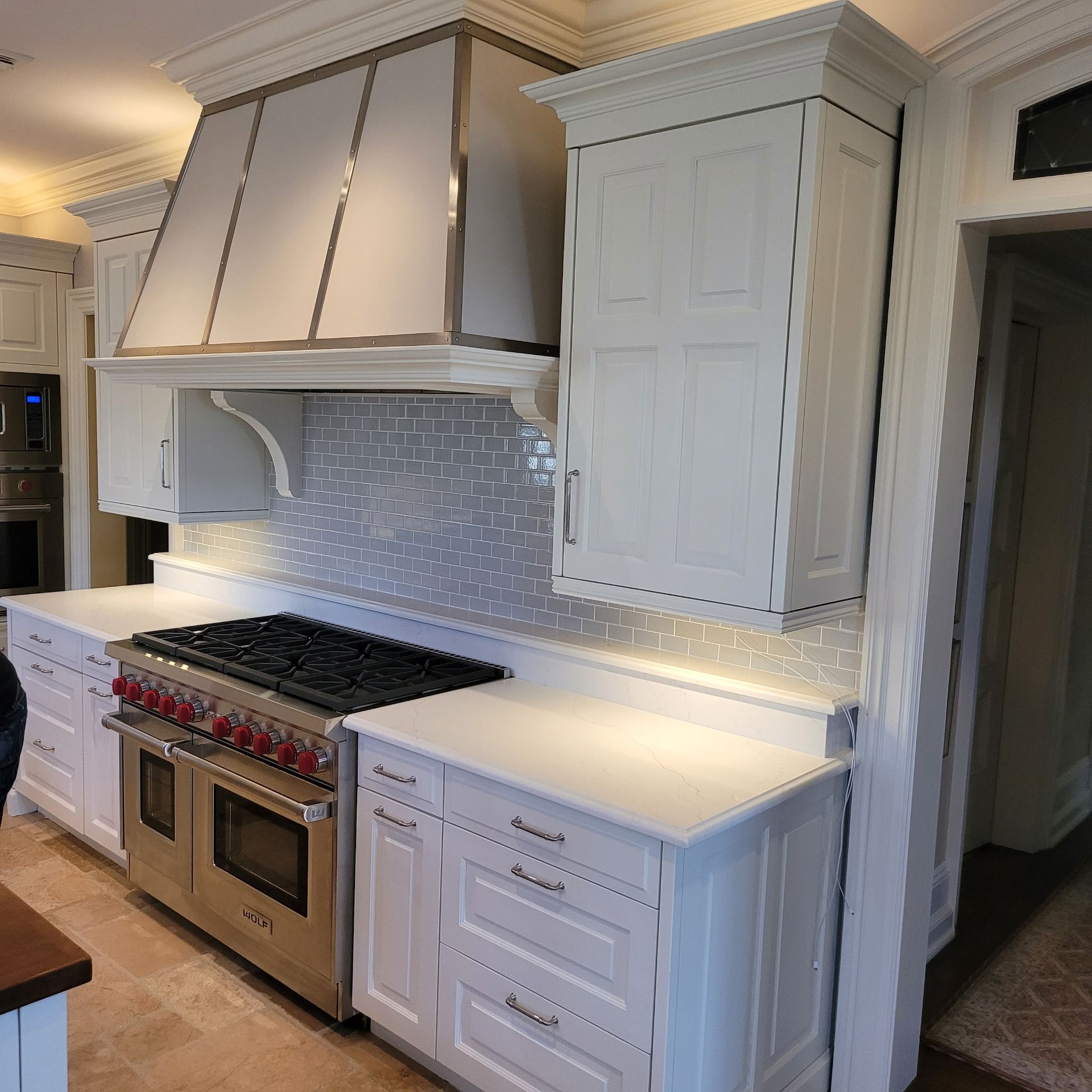 White kitchen with stainless steel range, hood, and cabinets.