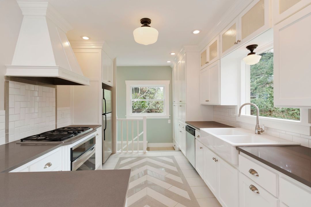 White kitchen with a gray countertop, stove, and herringbone floor.