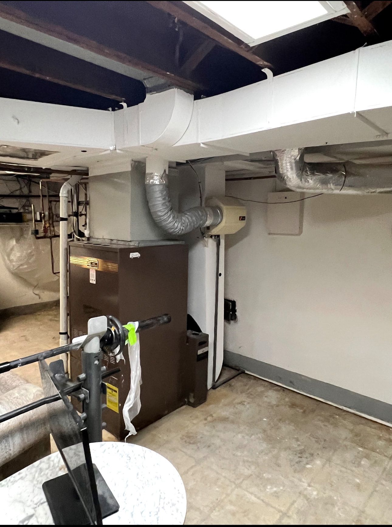 Furnace and water heater in a basement setting. Brown furnace, white water heater, and ductwork on the ceiling.