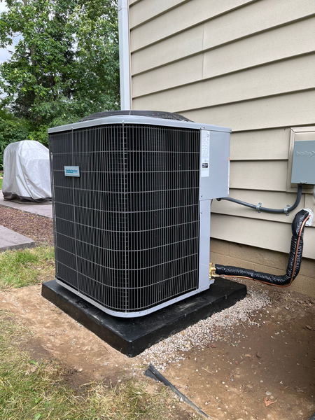 A large air conditioner is sitting on the side of a house.