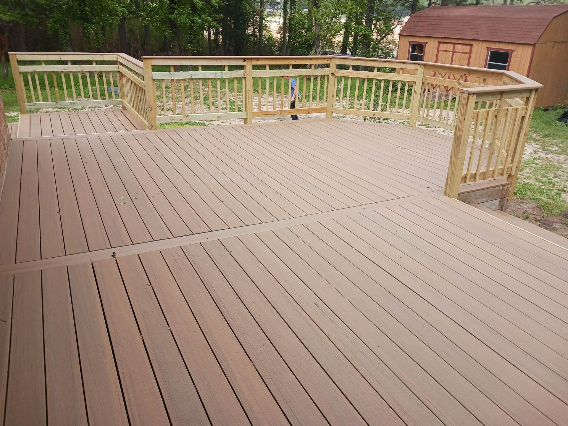 A wooden deck with a shed in the background