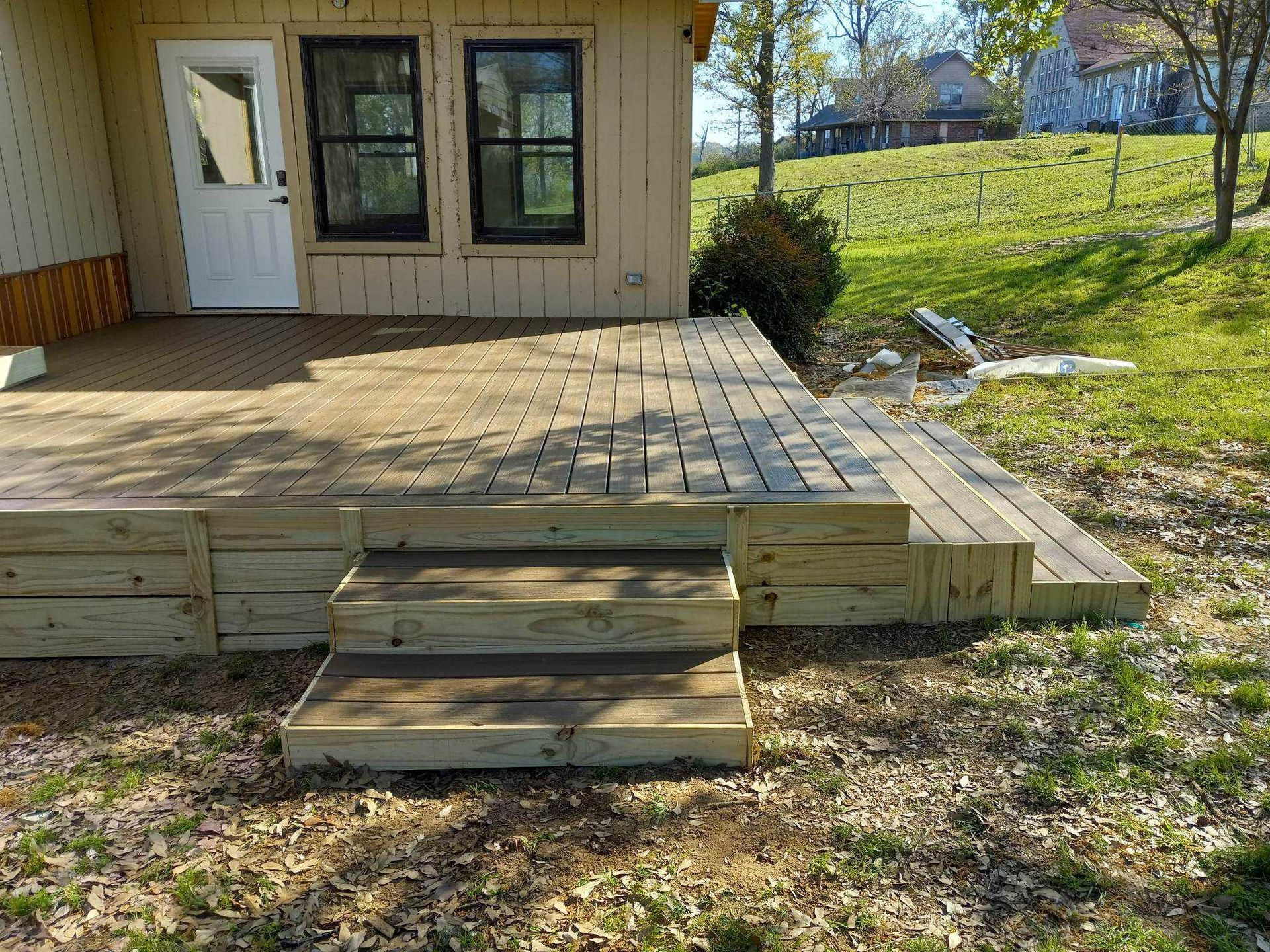 A wooden deck with stairs leading up to it in front of a house.