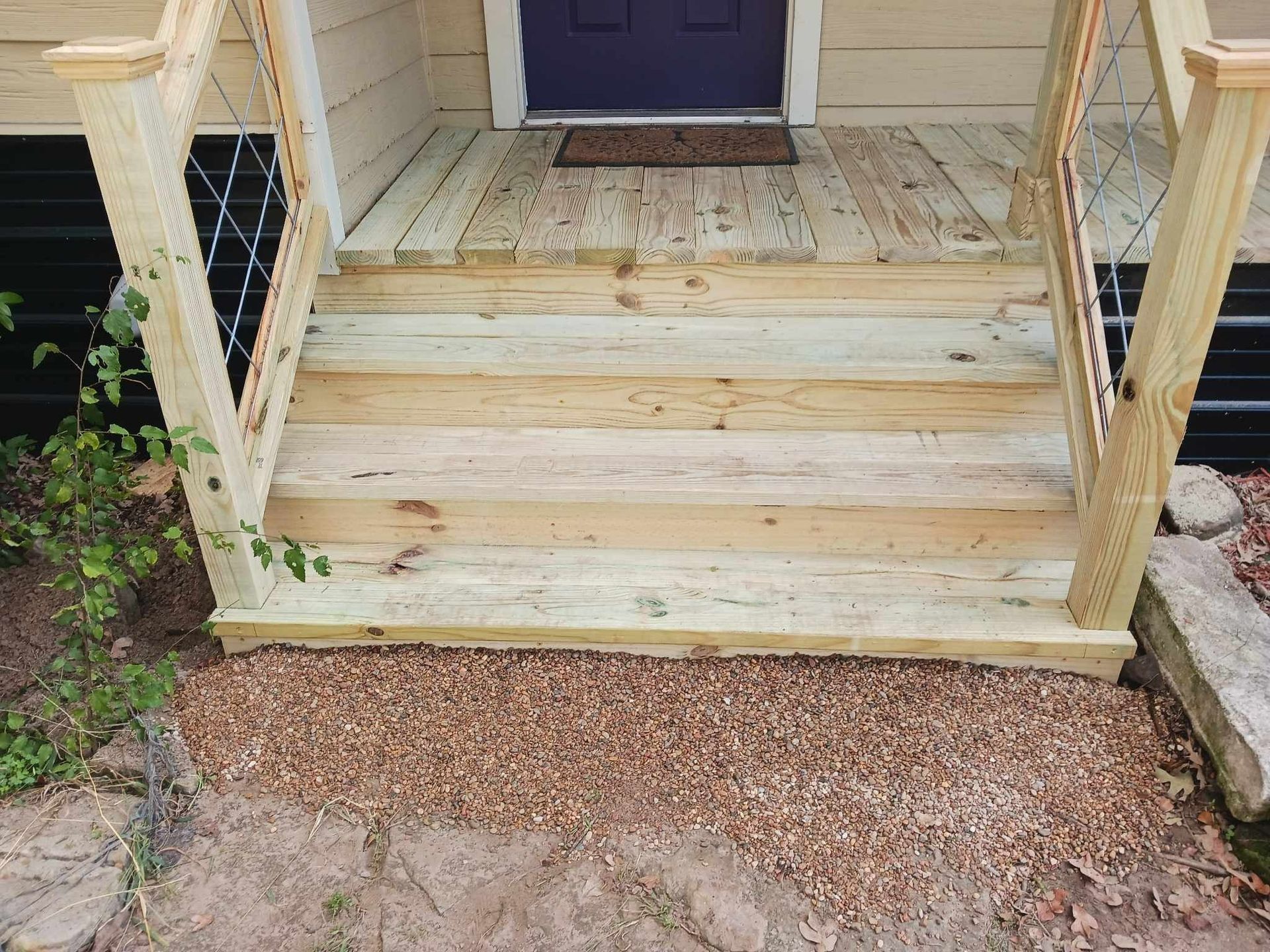 A wooden porch with stairs leading up to a purple door.