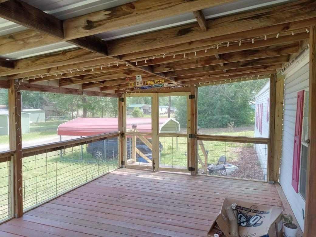 A screened in porch with a wooden deck and a ceiling fan.