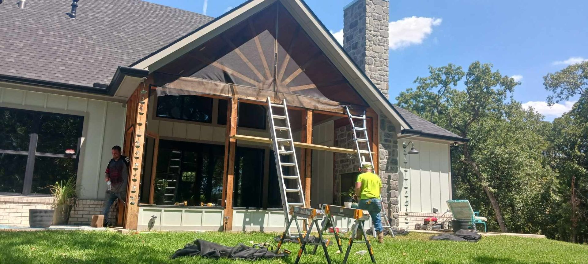 A man is standing in front of a house with a ladder.