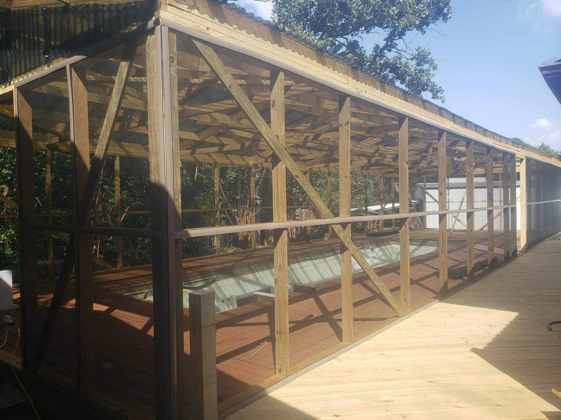 A screened in porch with a swimming pool in the background.