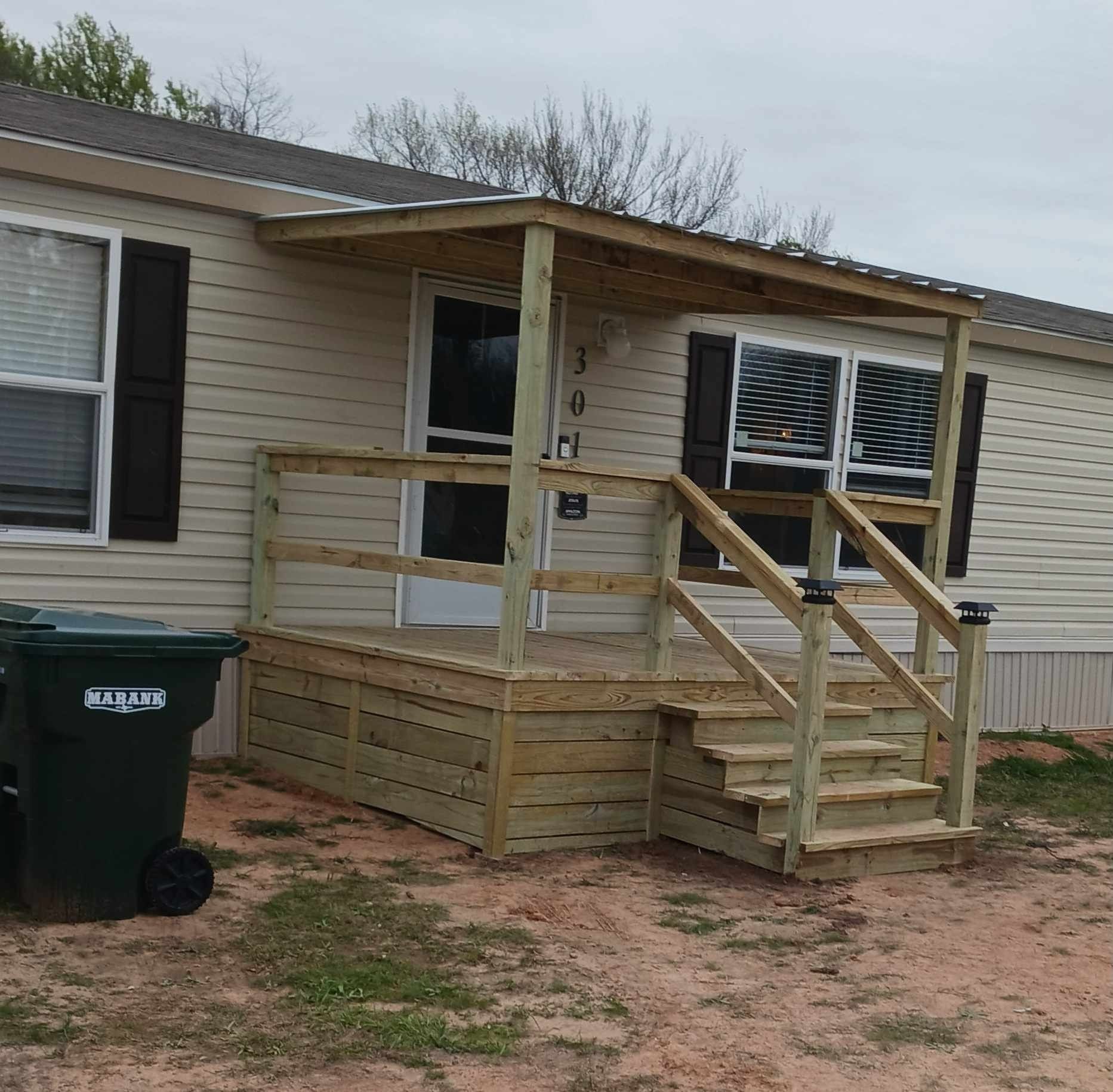 A mobile home with a green trash can in front of it