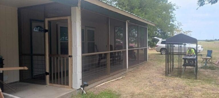 A screened in porch with a grill and chairs on it.