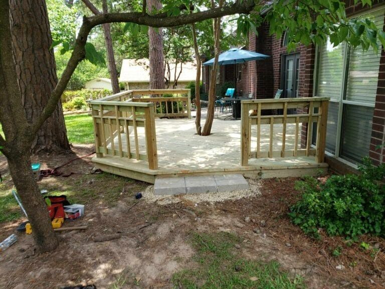 A wooden deck is being built in the backyard of a house.