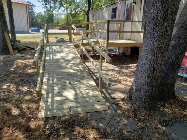 A wooden ramp with stairs leading to a mobile home.