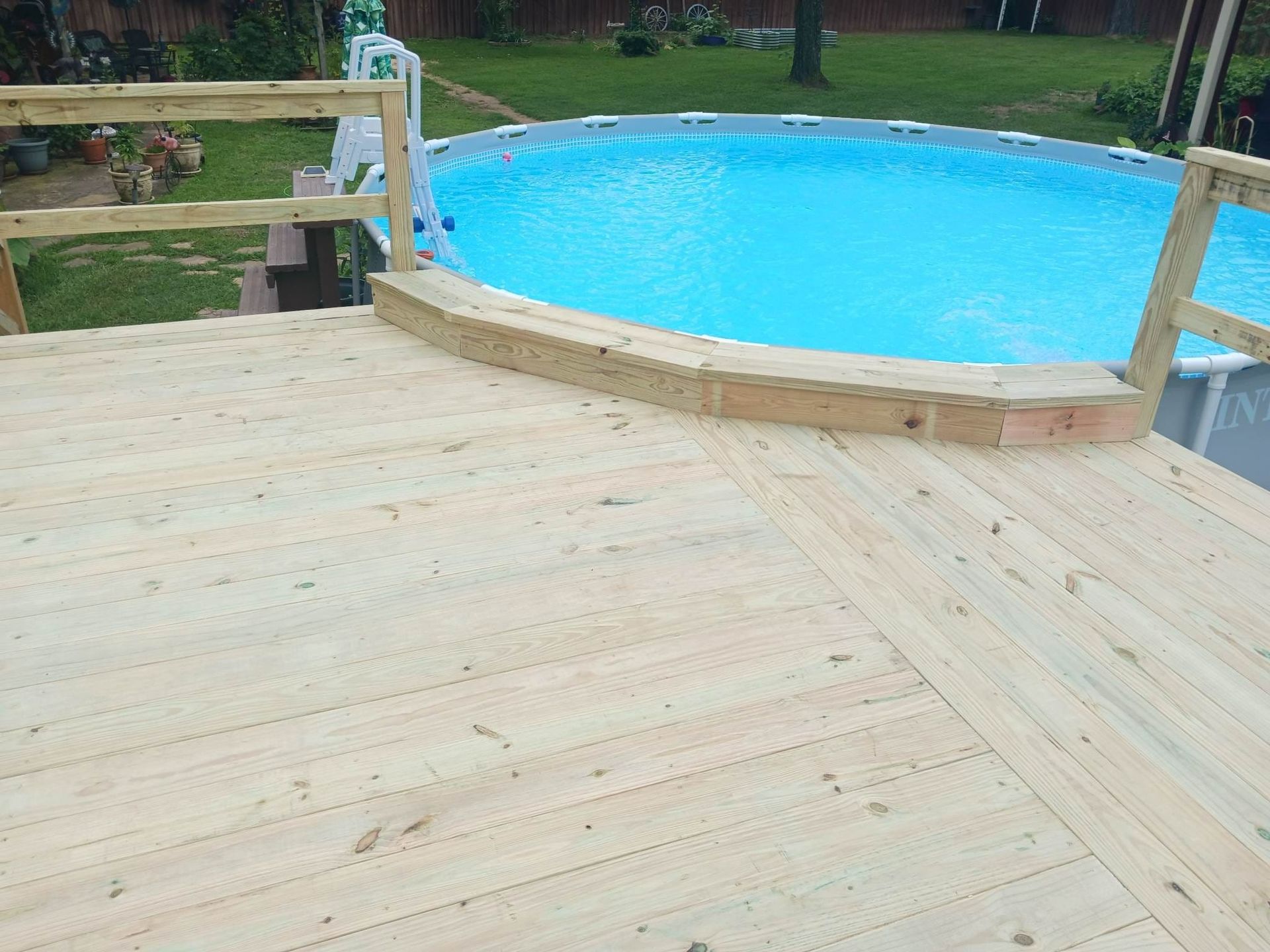 A wooden deck with a swimming pool in the background.