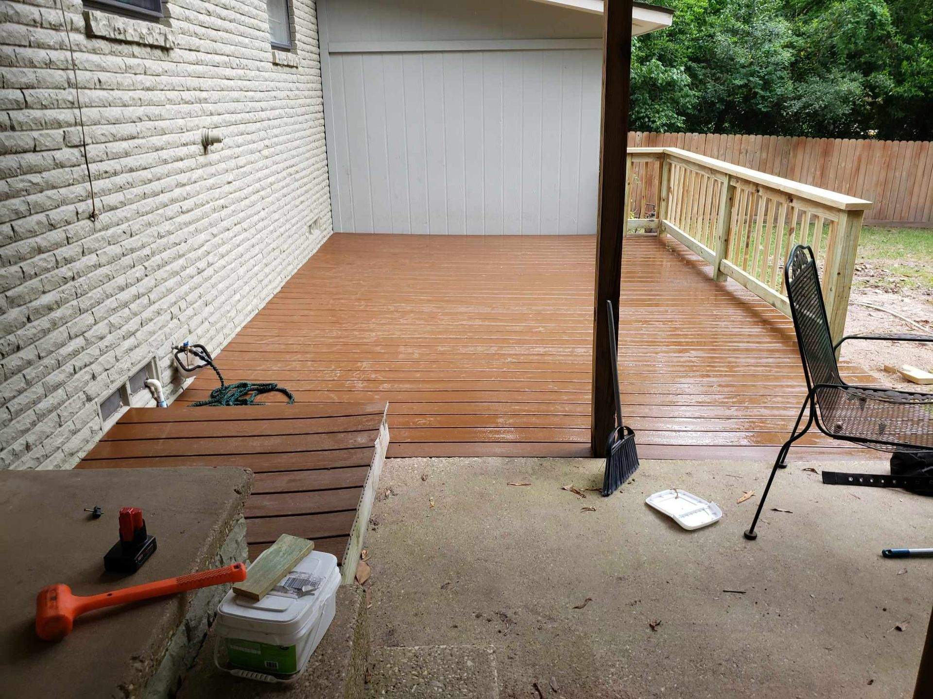 A wooden deck is being built in front of a white brick house.