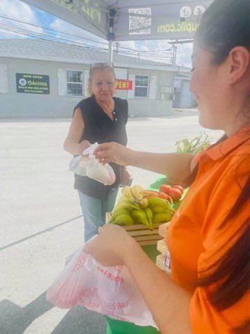 A woman is selling bananas to another woman at a market.