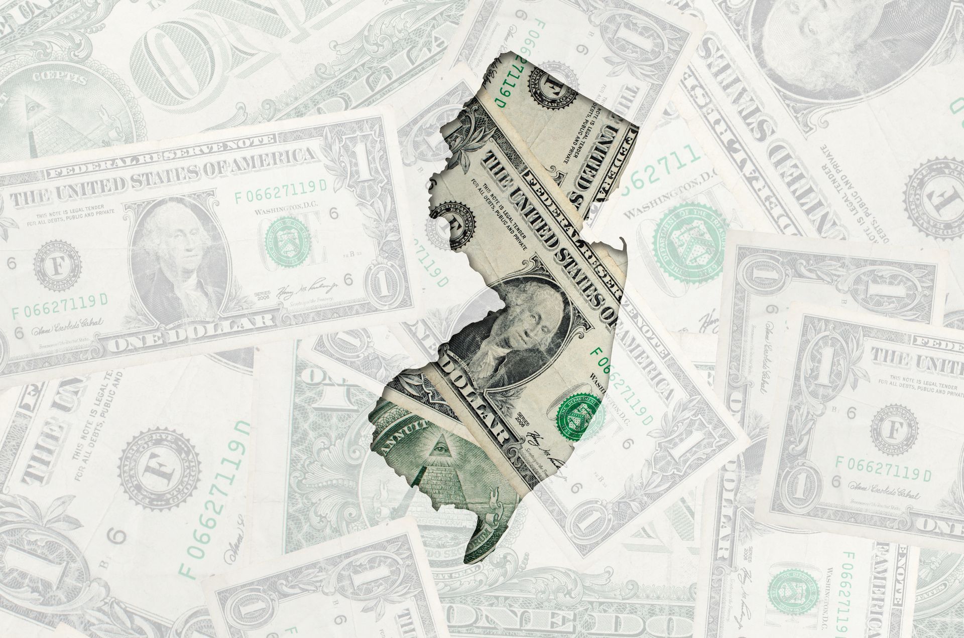 A dollar bill is laying on top of a pile of dollar bills.
