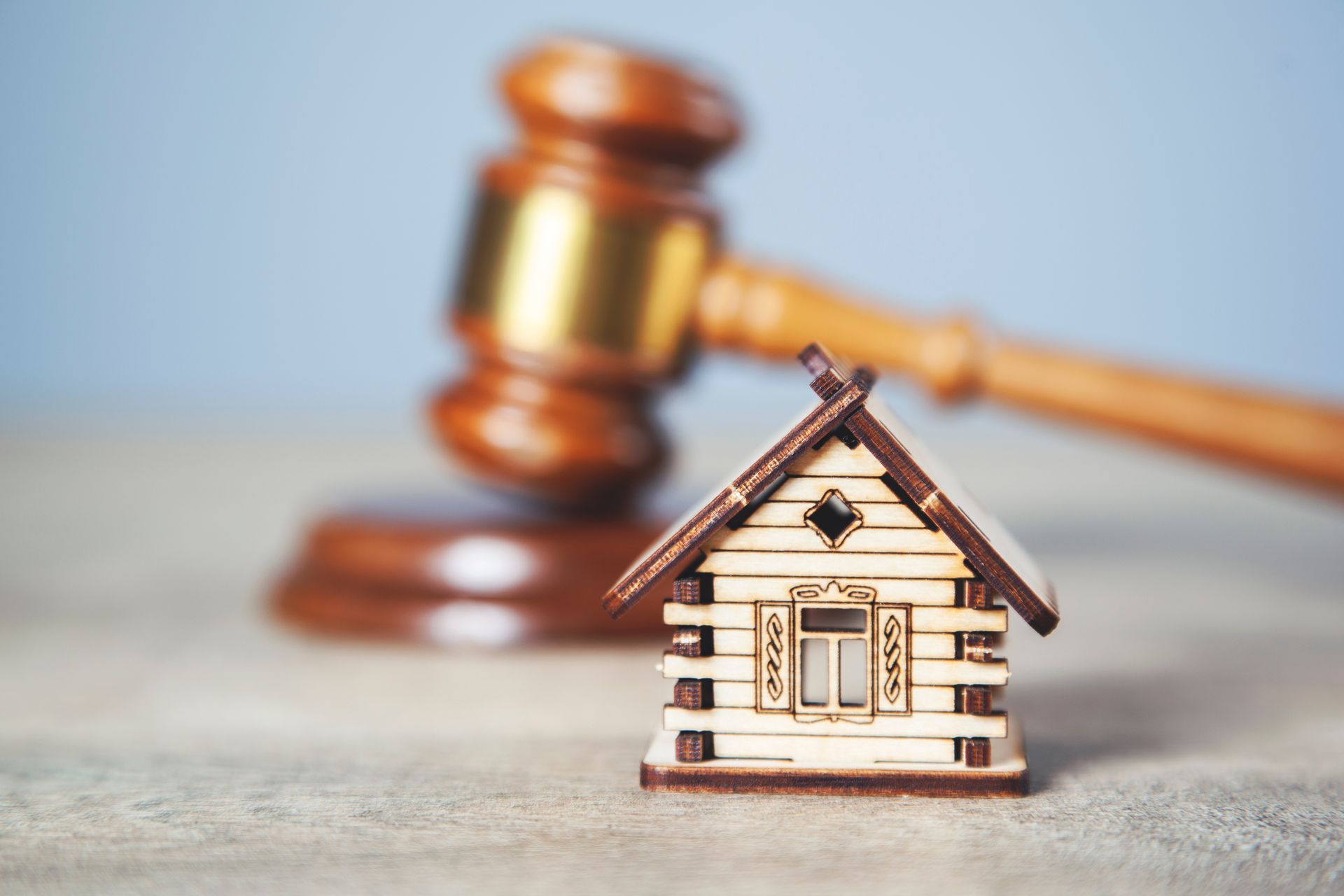 A small wooden house is sitting in front of a wooden gavel.