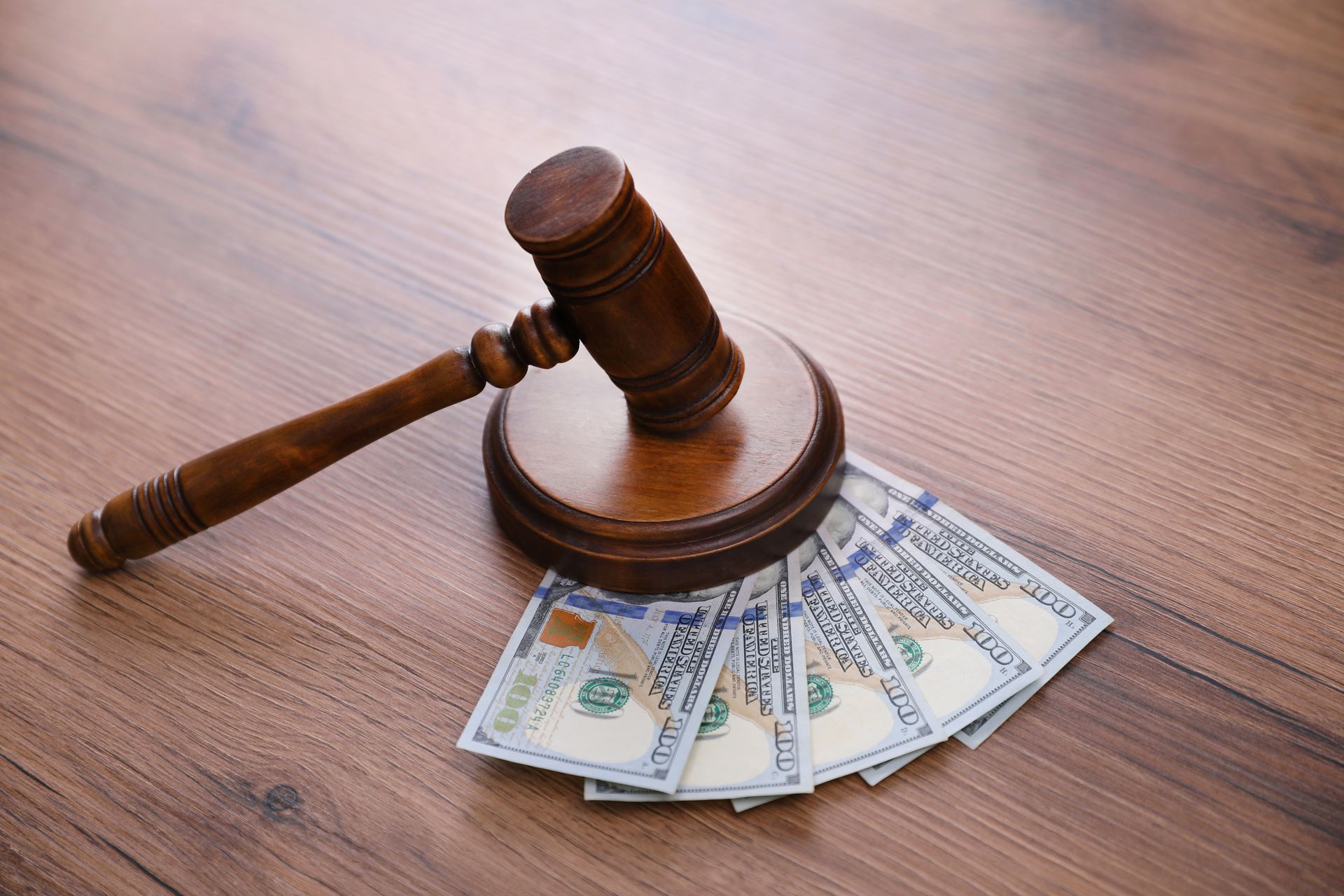 A wooden judge 's gavel is sitting on top of a pile of money on a wooden table.