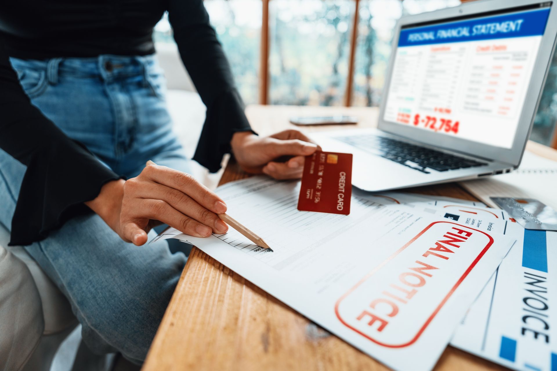 A person is sitting at a table with a laptop and a credit card.