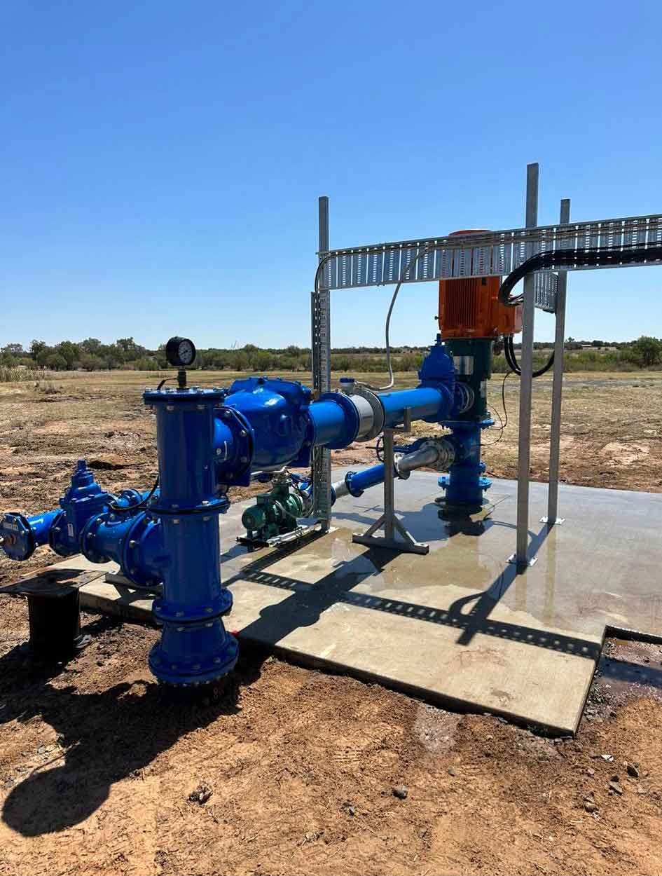 A bunch of blue pipes are sitting on top of a concrete platform in a field.