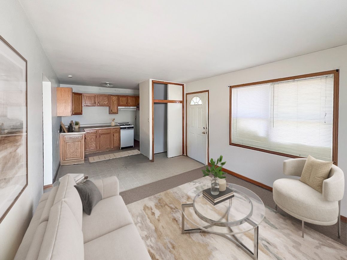 A living room with a couch , chair , coffee table and kitchen.