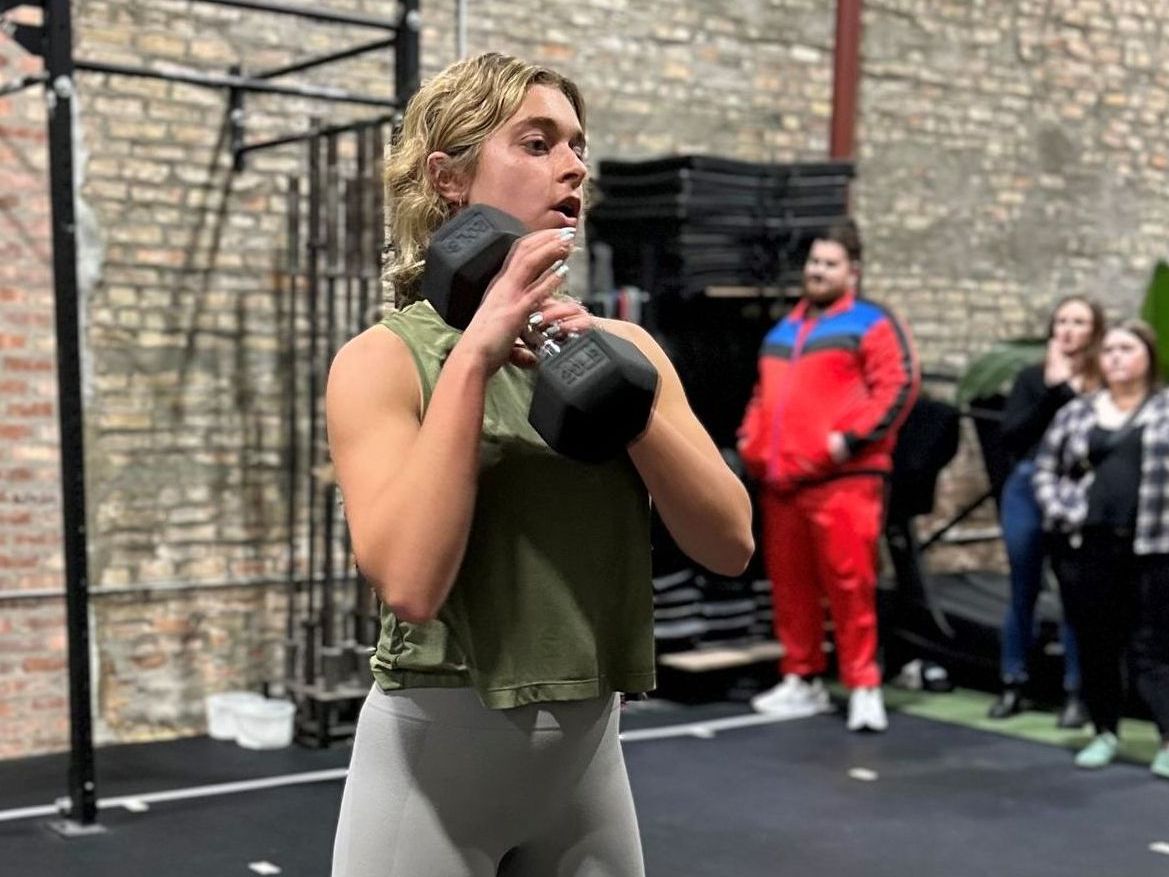 A woman is holding a dumbbell in her hands in a gym.
