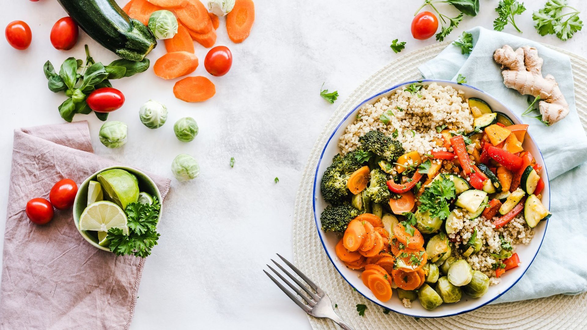 A bowl of vegetables and rice on a table with a fork.