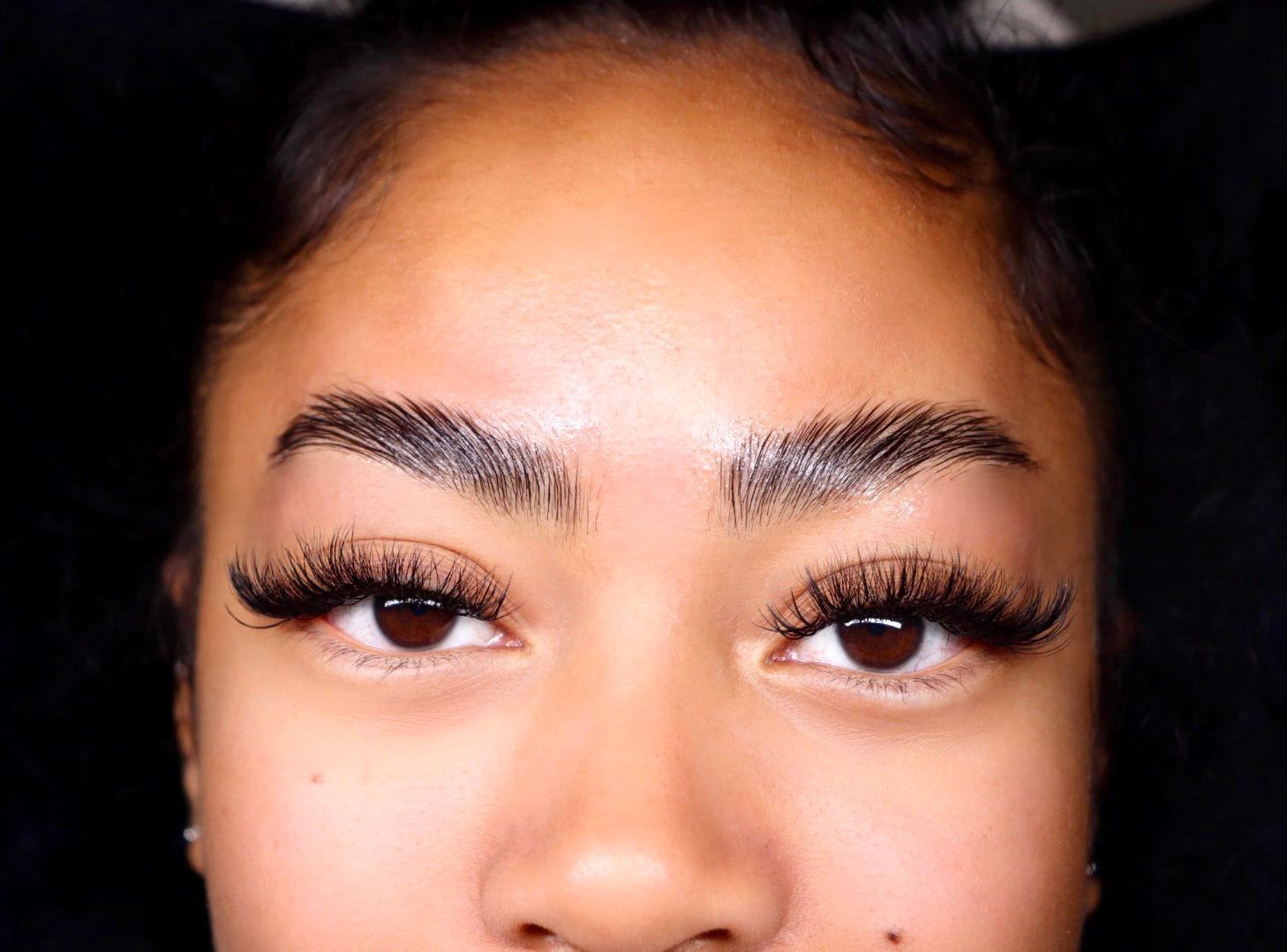 A close up of a woman 's face with long eyelashes and a necklace.