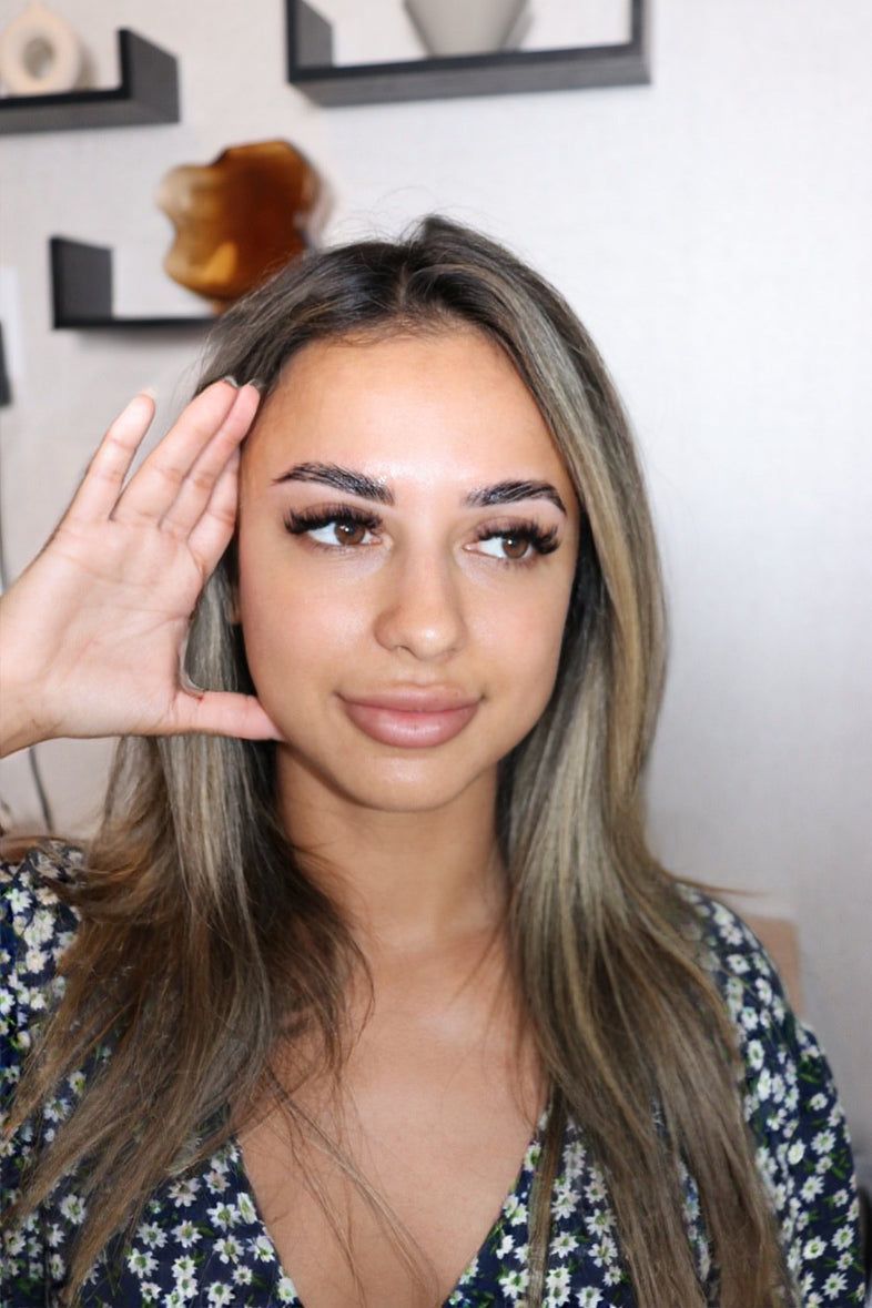 A woman is getting her eyelashes done by a makeup artist.