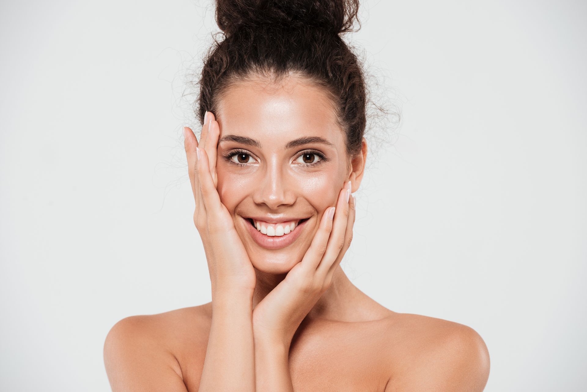 Portrait of a smiling woman touching her face over gray background