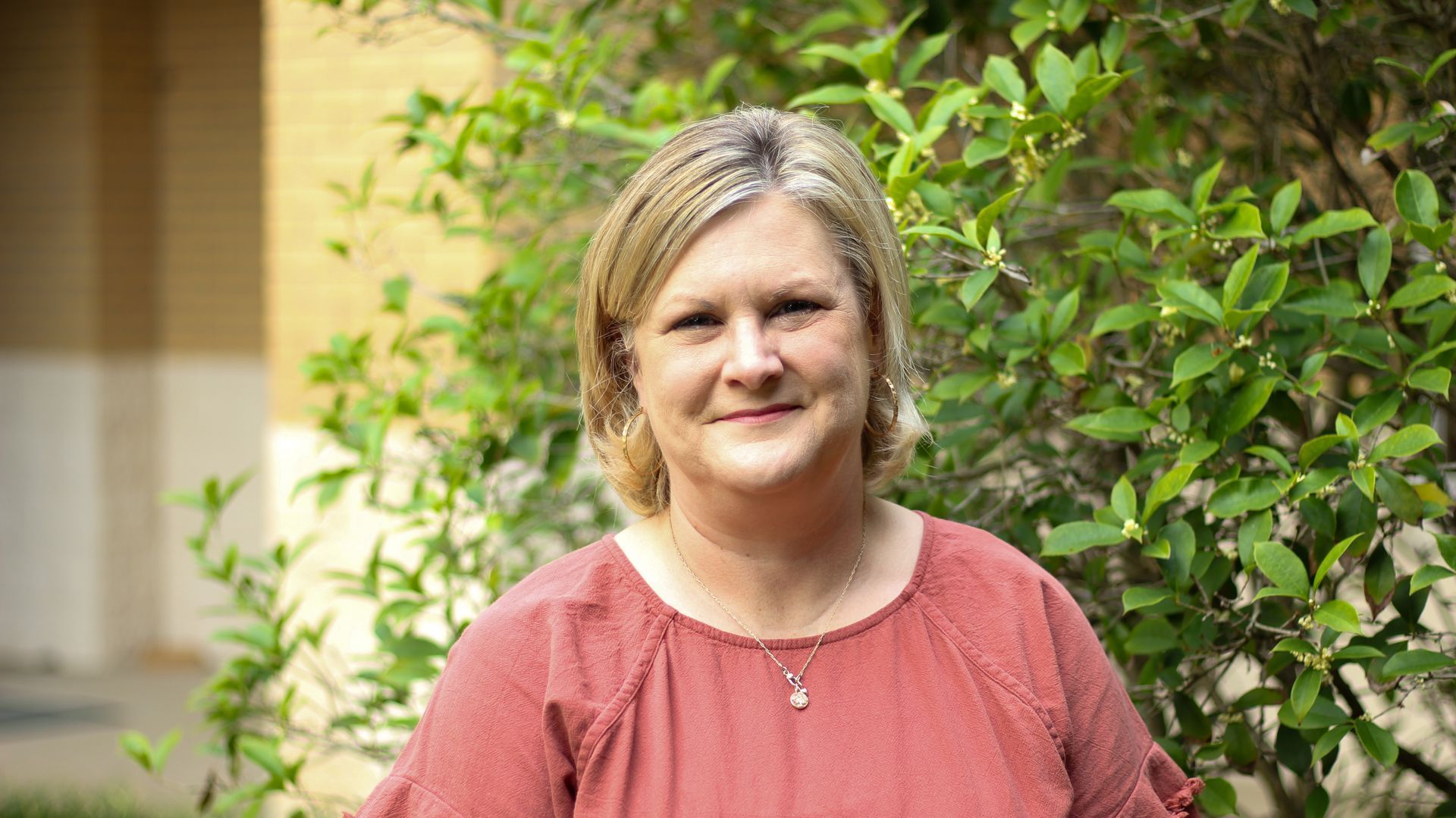 A woman is standing in front of a church looking at the camera.
